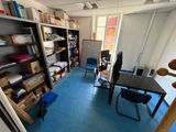 a room with a desk, chair, shelves, and other items
