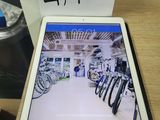 une tablette posée sur une table en bois, à côté d'une tasse de café