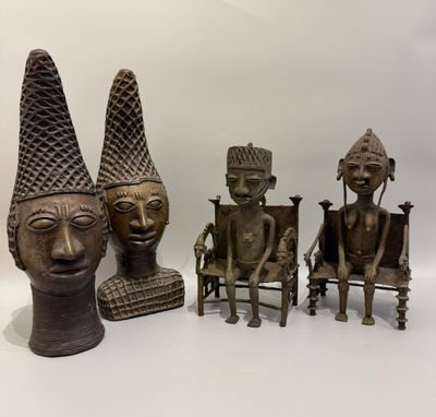trois statues en bronze représentant des personnes assises sur des chaises, coiffées de cônes