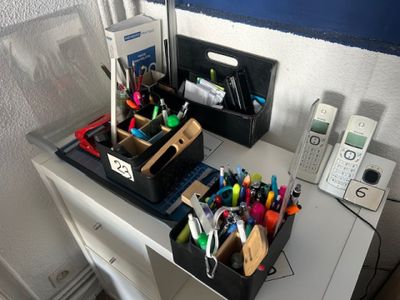 a desk with a phone, pen holder, and other office supplies on it