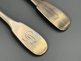 une paire de cuillères en argent sur lesquelles est gravée la lettre « s »
