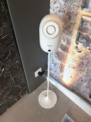 un haut-parleur blanc posé sur un pied, à côté d'une porte