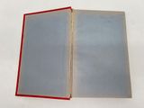 an open book on a white surface with a red border