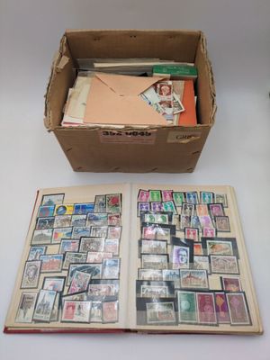 un livre ouvert posé sur une table, à côté d'une boîte de timbres