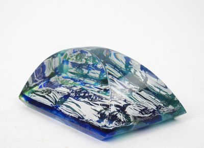 un objet en verre bleu et vert posé sur une surface blanche