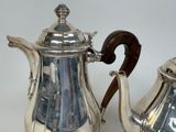 two silver teapots sitting next to each other on a table