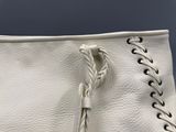 sac à main en cuir blanc avec des anses tressées sur fond bleu