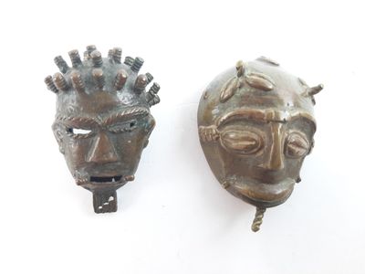 pair of bronze masks on a white background, one of which is wearing a crown