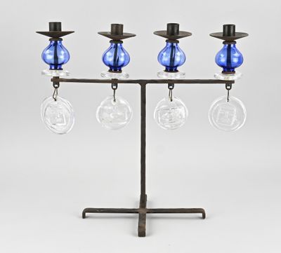 three blue glass vases are on a metal stand with a candle holder