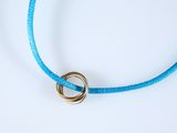 collier en cordon bleu orné de deux anneaux dorés sur fond blanc