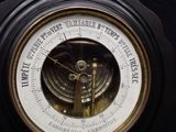 a clock with a barometer attached to it ' s side