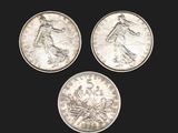 three silver coins, one of which is a woman and one of which is a man