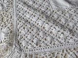 a white crochet bib laying on top of a bed