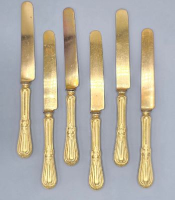 four gold plated knives and a knife holder on a table