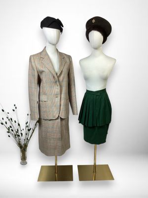 two mannequins dressed in a suit and skirt are standing next to a vase of flowers