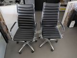 pair of black leather office chairs with chrome arms and casteors