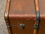 an old brown suitcase sitting on the ground