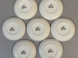 six white plates with black writing on them sitting on a table