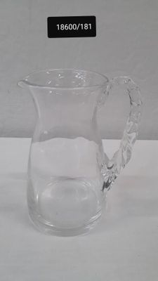a clear glass pitcher with a handle on a table