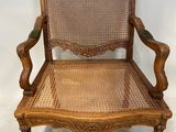 une chaise en bois avec une assise en osier et des accoudoirs