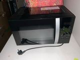 a microwave sitting on top of a table with a bag on it