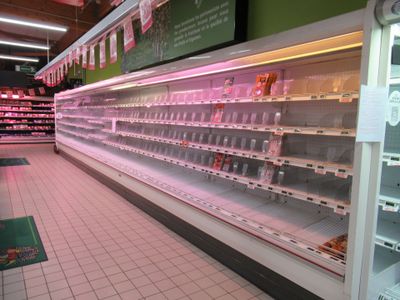 many empty shelves in a grocery store with pink lights