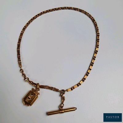 gold plated bracelet with charms and a pen on a white surface