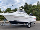 a white boat on a trailer parked in the parking lot
