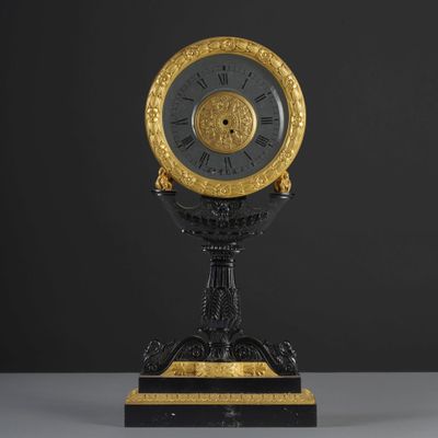 an antique black and gold clock with roman numerals on a pedestal