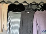 many sweaters hanging on a clothes rack in a closet