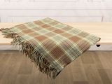 a plaid blanket on a wooden table in front of a white wall