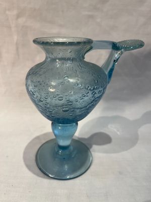 un vase en verre bleu muni d'une anse, posé sur une table