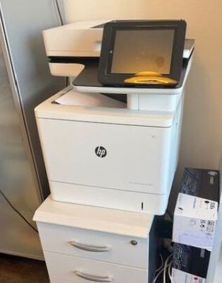 une imprimante posée sur une armoire, à côté d'un réfrigérateur