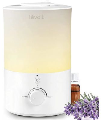 un humidificateur blanc, avec des fleurs de lavande à côté et un flacon d'huiles essentielles