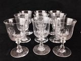 six clear glass goblets sitting on top of a black table