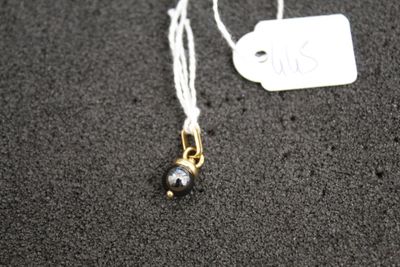 a necklace with a black bead and a white tag on it