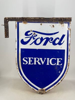 an old blue and white ford service sign sitting on top of a table