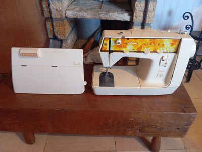 une machine à coudre posée sur une table en bois devant une cheminée