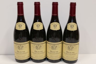 quatre bouteilles de vin rouge sont alignées sur une table