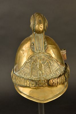un vieux casque doré surmonté d'un éventail