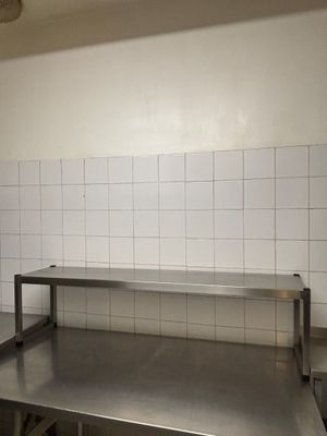 a stainless steel counter in a kitchen with white tiles on the walls