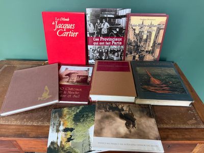 Plusieurs livres sont posés sur une table en bois devant un mur vert.