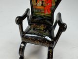 a miniature chair with a painting on the back of it
