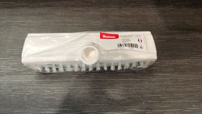 une brosse en plastique posée sur une table, sur laquelle figure un code-barres