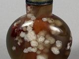 a small glass bottle with a green ball on top of it