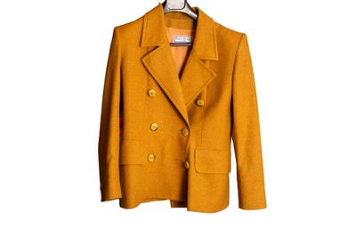 une veste orange suspendue à un cintre sur un mur blanc