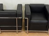 pair of black leather lounge chairs with chrome legs