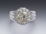une bague en or blanc et diamants, avec une pierre centrale entourée de petits diamants