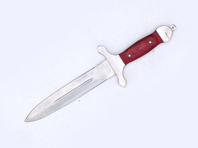 un couteau au manche rouge posé sur une surface blanche