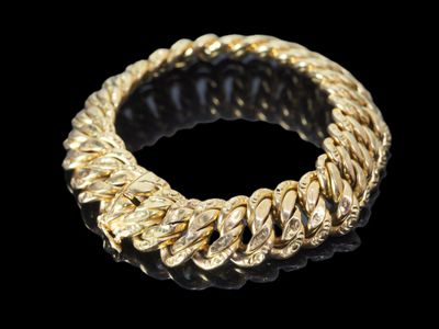 gros plan d'un bracelet en or sur fond noir